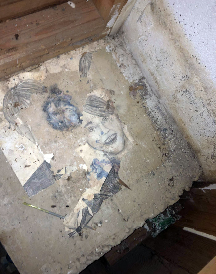 Faded drawing found under old floorboards showing a face and abstract shapes in a dusty, aged home space.