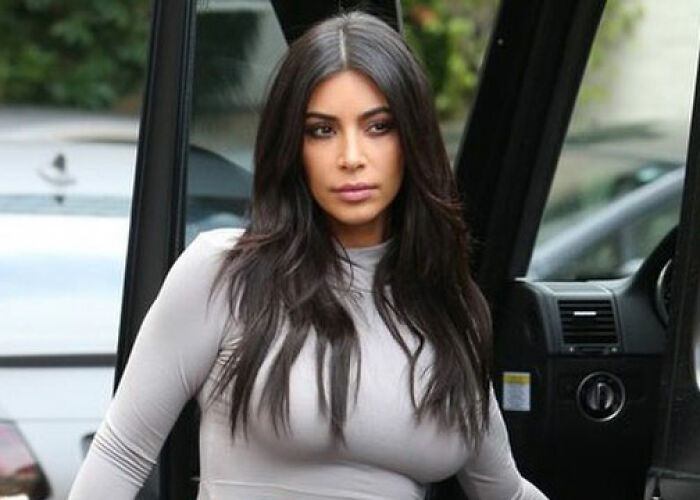 Kim Kardashian of the KarJenner clan stepping out of a car wearing a fitted gray top, looking serious and composed. - 15