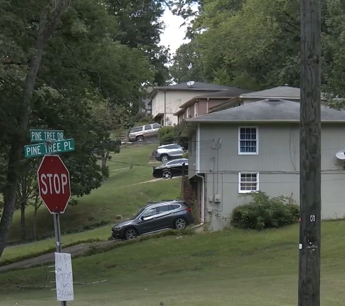 Residential neighborhood with parked cars and stop sign near Pine Tree Drive and Pine Tree Place where 3-year-old boy in foster care found. - 3