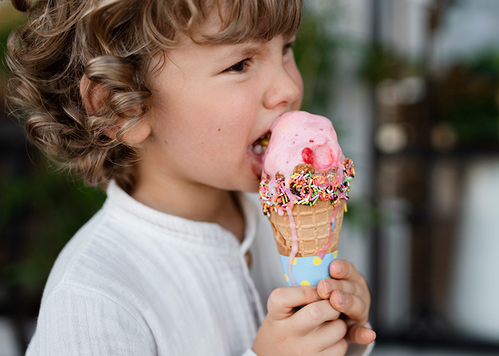 Young child enjoying a colorful ice cream cone, illustrating funny moments parents reveal in hilarious lies to kids.