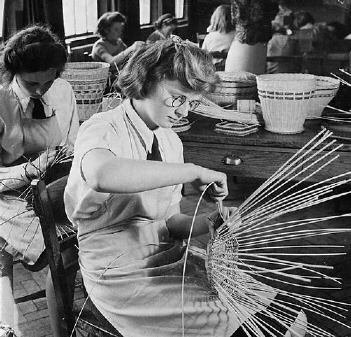Girls weaving baskets in a school craft class, showcasing schools worldwide activities during World War II.