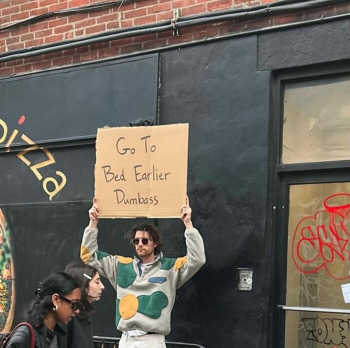 Man holding a sign with a humorous message on the street, example of Dude With The Sign capturing common thoughts.