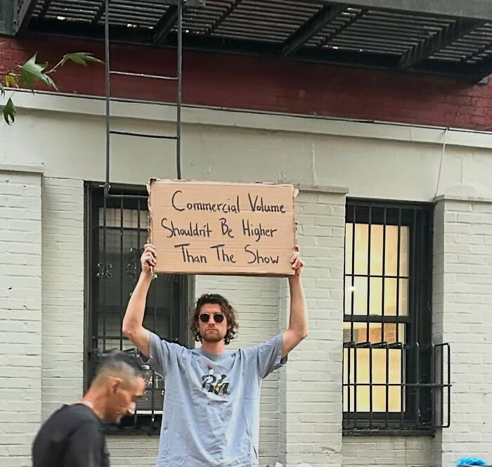 Man holding a cardboard sign with a message, embodying the dude with the sign viral humor and social commentary.