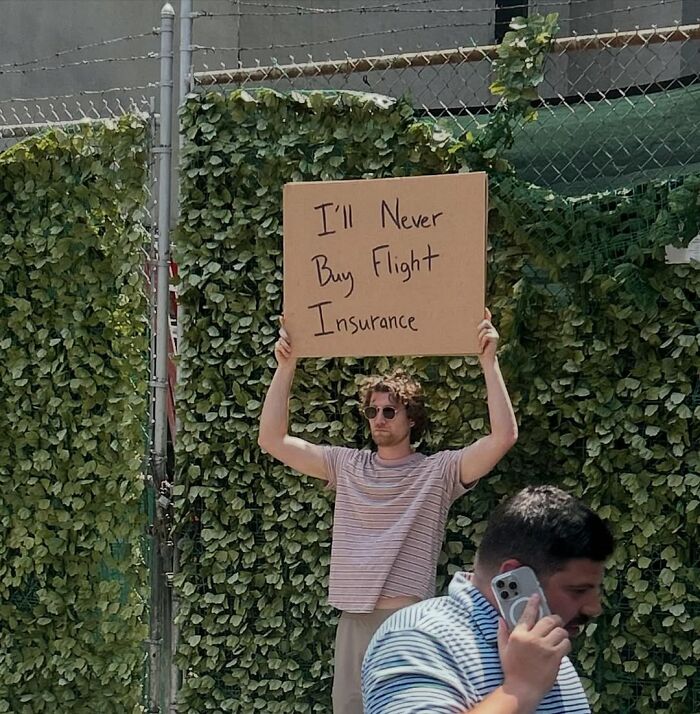 Man holding a sign saying never buy flight insurance in an outdoor urban setting, dude with the sign humor concept.