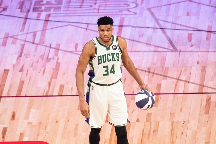 Professional basketball player from poverty to super wealthy, dribbling a ball on a brightly lit indoor court.