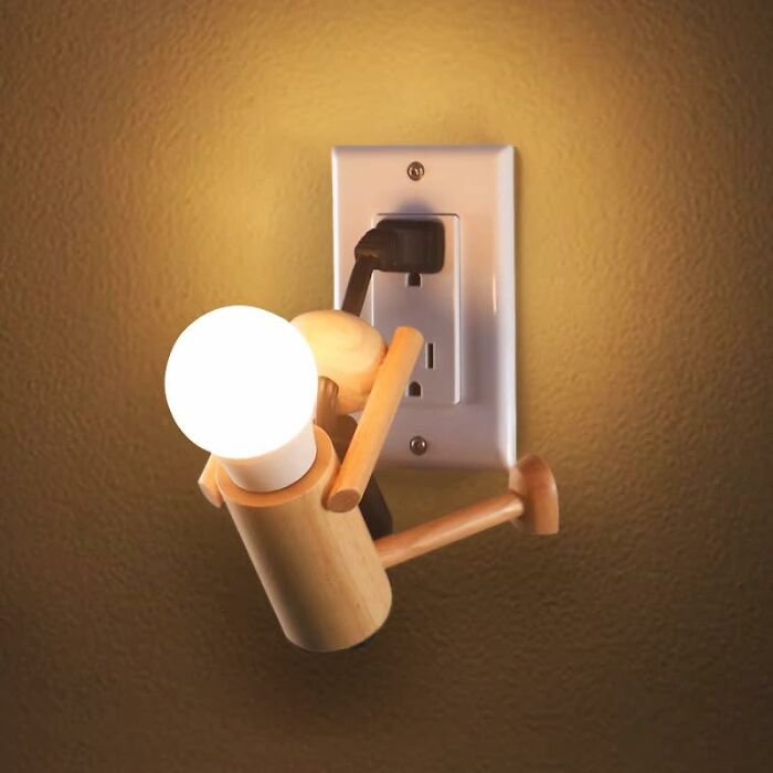 Wooden figure night light plugged into wall socket, showcasing one of the weirdest picks found on Amazon.