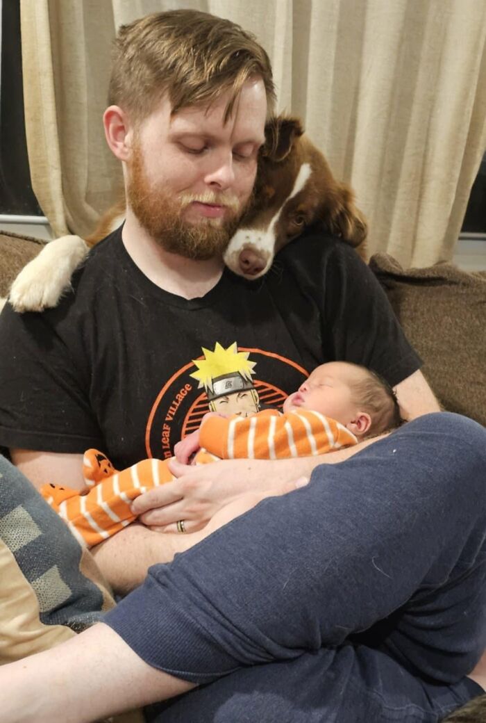 Man cradling newborn baby with dog resting head on his shoulder, capturing the beauty of planet Earth and family bonds.
