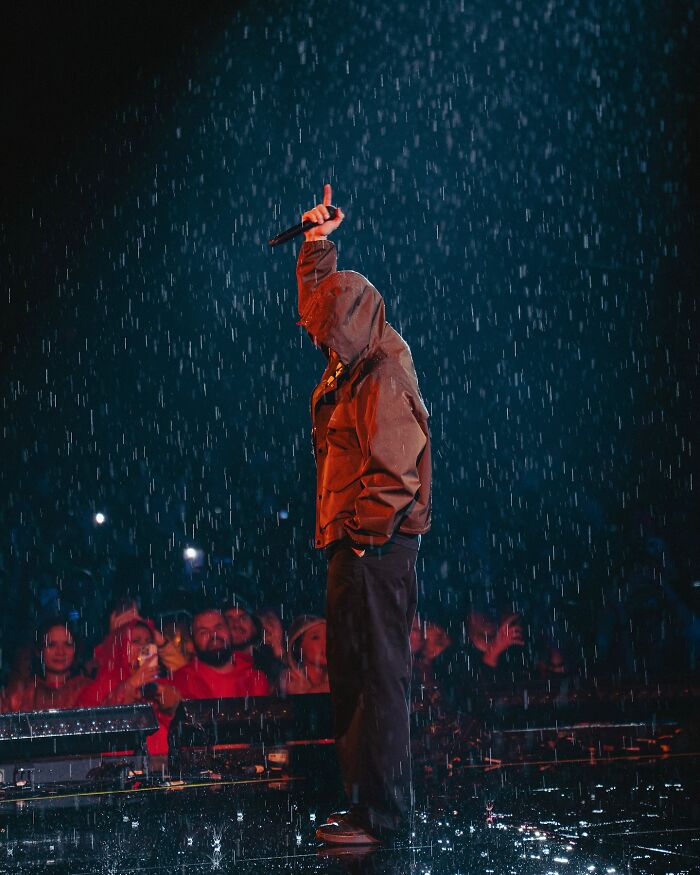 Performer on stage in rain during Justin Timberlake Romania show with audience in the background capturing the moment on phones