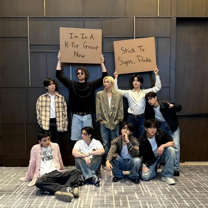Group photo with two holding signs, reflecting the humor and wit of dude with the sign popular memes and trends.