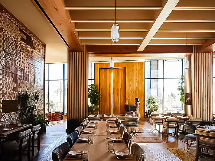 Modern restaurant interior with wooden design, empty tables set for dining, reflecting job loss consequences in workplace settings.
