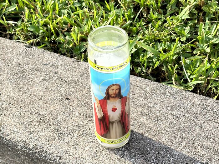 Religious candle on sidewalk with image of Jesus, representing unusual items found on patients that shocked medical professionals.