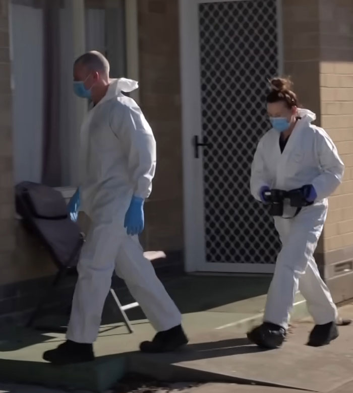 Two forensic investigators in protective suits and masks at crime scene of reality star charged with murder case.
