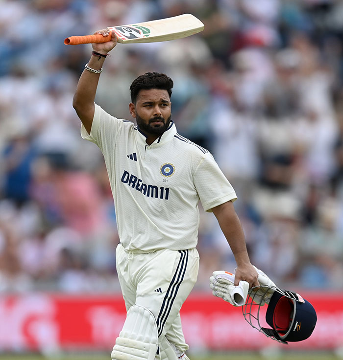 Top athlete on cricket field raising bat and helmet, mocked after interacting with fake influencer at Wimbledon event.