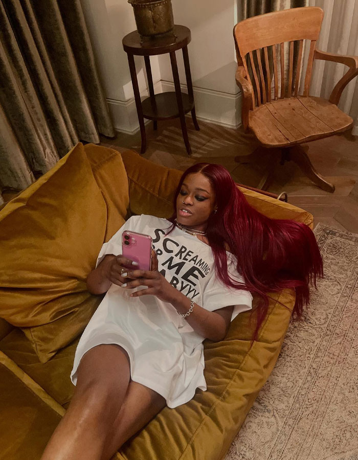 Person lounging on a mustard couch looking at a smartphone, related to Conor McGregor leaked x-rated pic news.