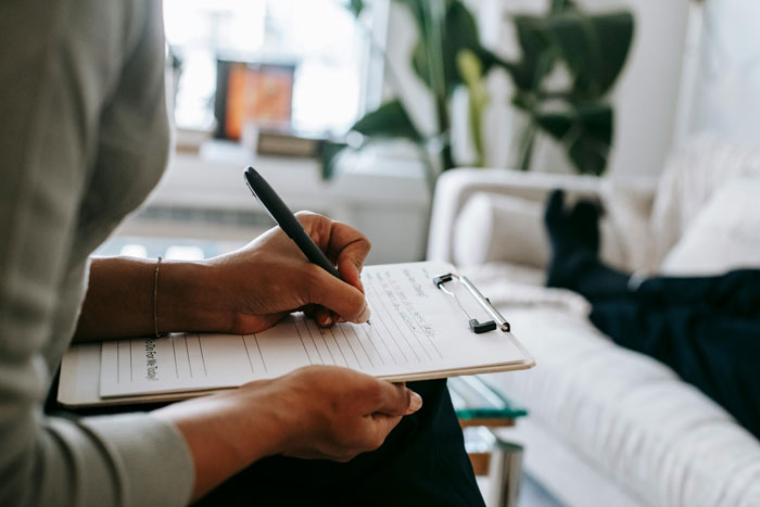 Therapist taking notes on clipboard during a counseling session focused on differences between men and women in a cozy office. - 13