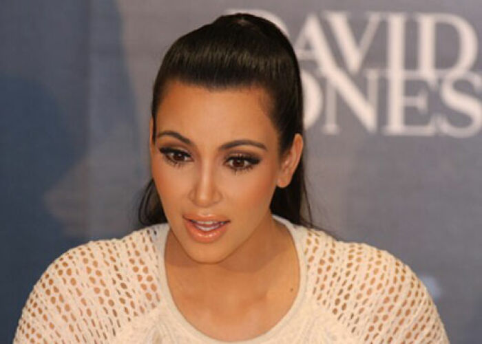 Kim Kardashian at an event, wearing a white top with detailed makeup, representing the KarJenner clan controversies. - 3