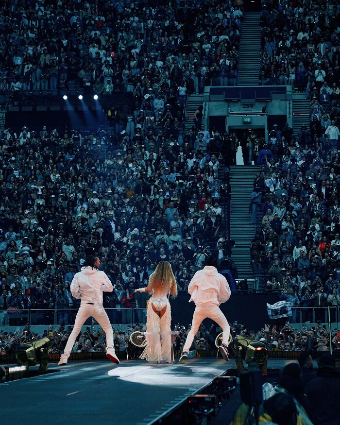 Beyonc&eacute; performing on stage at Cowboy Carter concert with dancers in front of a large, energetic crowd.