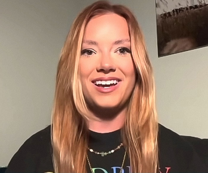 Woman recording CEO cheating on Coldplay kiss cam sharing her experience in a casual indoor setting.