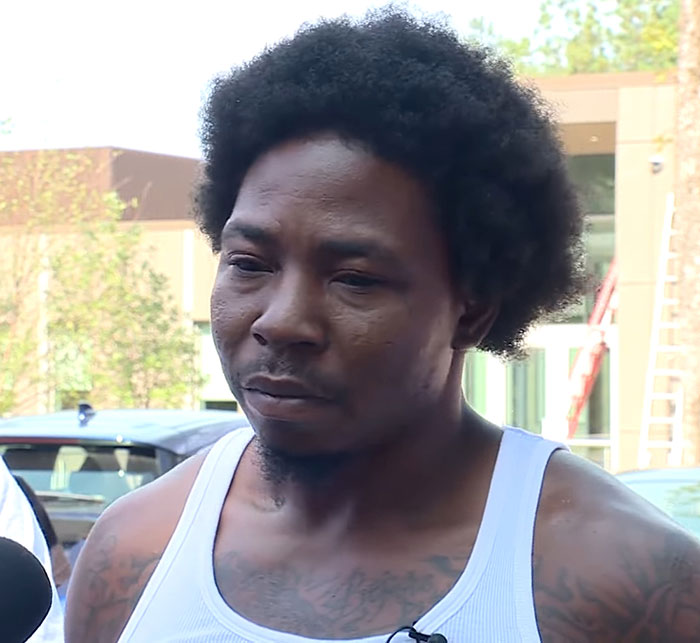 Man with afro hairstyle wearing a white tank top speaking outside, related to 3-year-old boy in temporary foster care incident. - 5