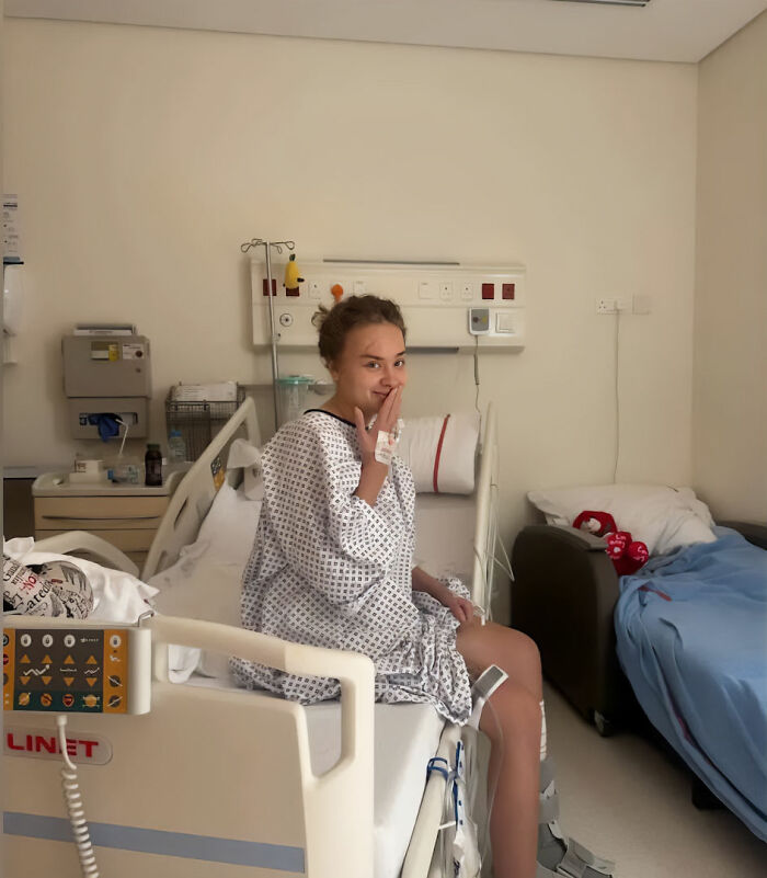 Young woman wearing a hospital gown sitting on a hospital bed, recovering after being scalped in Dubai incident. - 6