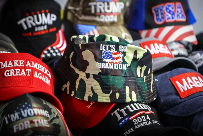 CAMO bucket hat with Let's Go Brandon slogan surrounded by Trump and MAGA hats symbolizing consequences of their own stupidity.