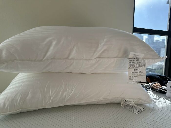 Two white pillows stacked on a bed showing tags, representing best sellers that topped the charts Prime Day.