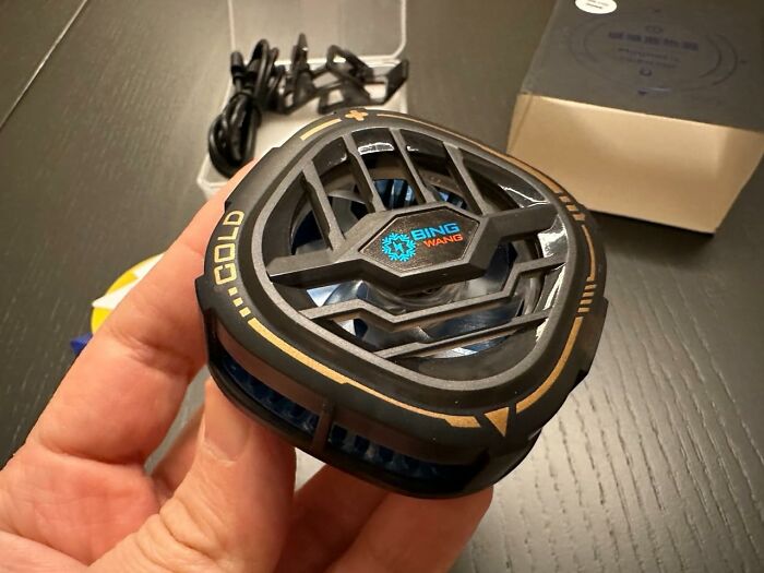 Hand holding a compact portable fan designed for heatwave hacks to help stay cool during summer heat.