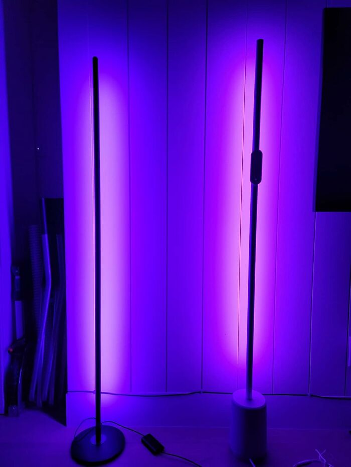 Two tall LED floor lamps emitting vibrant purple light against a white wall, popular Amazon wished for items this week.