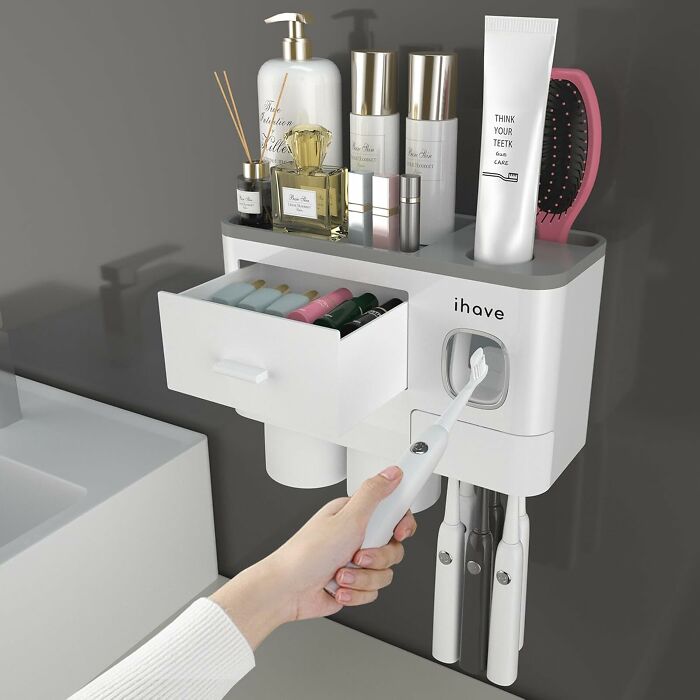 Under-the-radar finds bathroom organizer with toothbrush holder, storage drawer, and toiletries on a gray wall near sink.