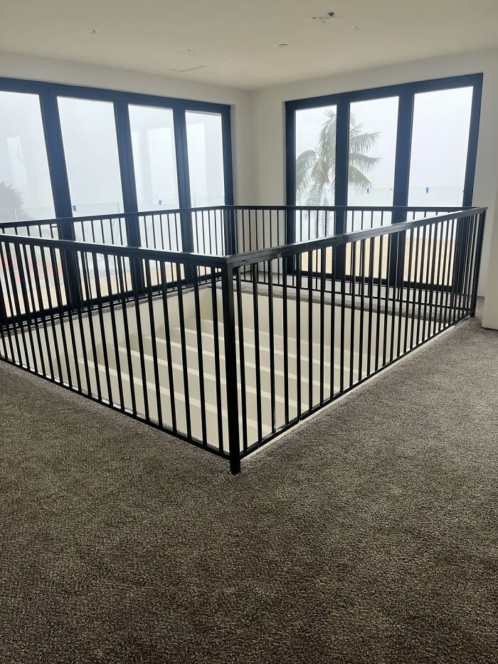 Modern home interior with stairwell surrounded by black metal railing, showing a creative home design fail.