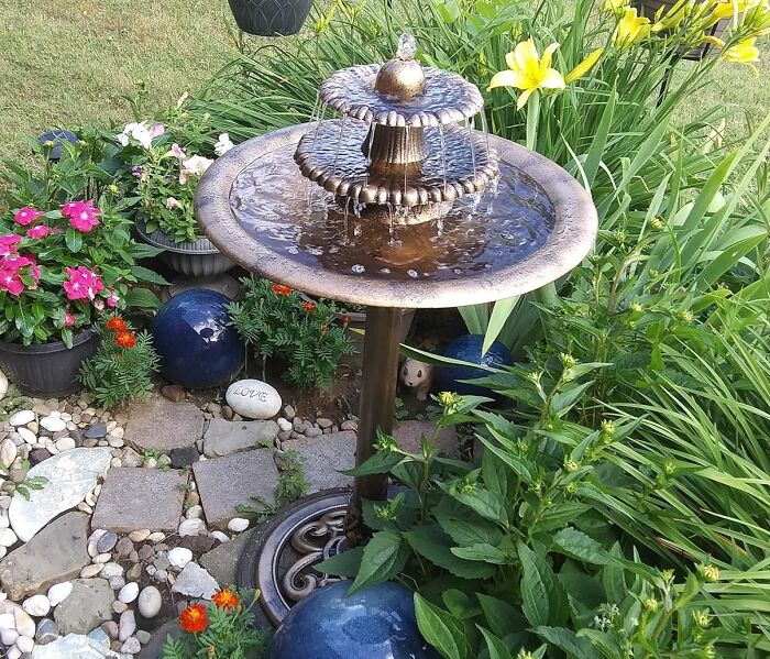 Decorative garden water fountain surrounded by colorful flowers and plants enhancing garden gadgets setup.