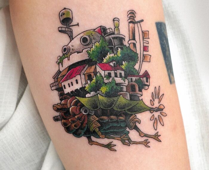 Colorful tattoo of a mechanical walking house with trees and smoke stacks, showcasing creative detail in the best tattoos collection.