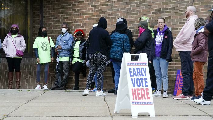 People standing in line outside a building to early vote, highlighting consequences of poor decisions at work.
