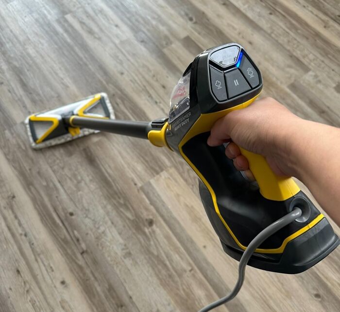 Hand holding a yellow and black steam mop cleaning a wood floor, one of the top 5-star Prime Day finds.
