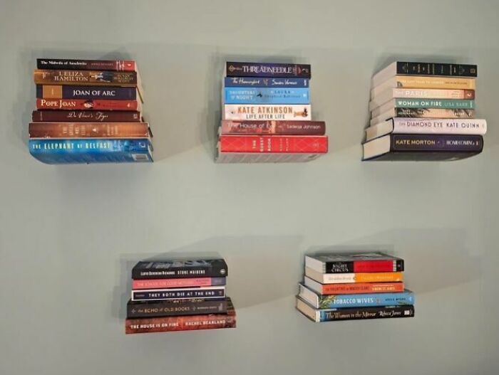 Floating bookshelves neatly holding stacked books on a wall, ideal for frantic panic before guests arrive cleaning style.