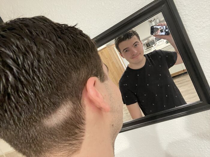 Young man with a haircut mistake taking a selfie in the mirror, illustrating salon glow-up gone wrong stories.