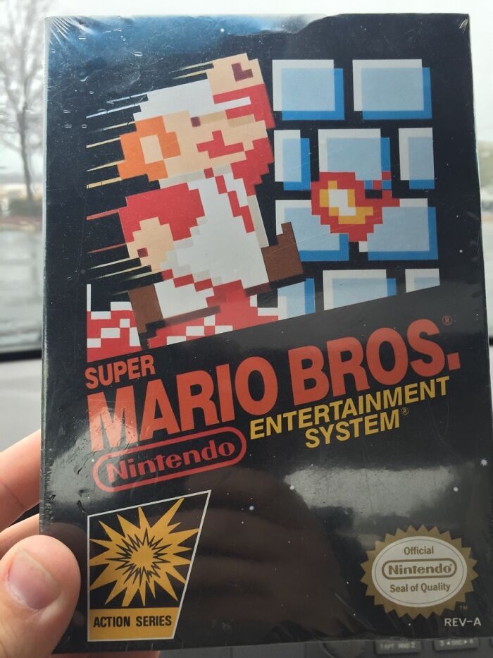 Sealed vintage Super Mario Bros Nintendo collectible item held up against a window in natural light.