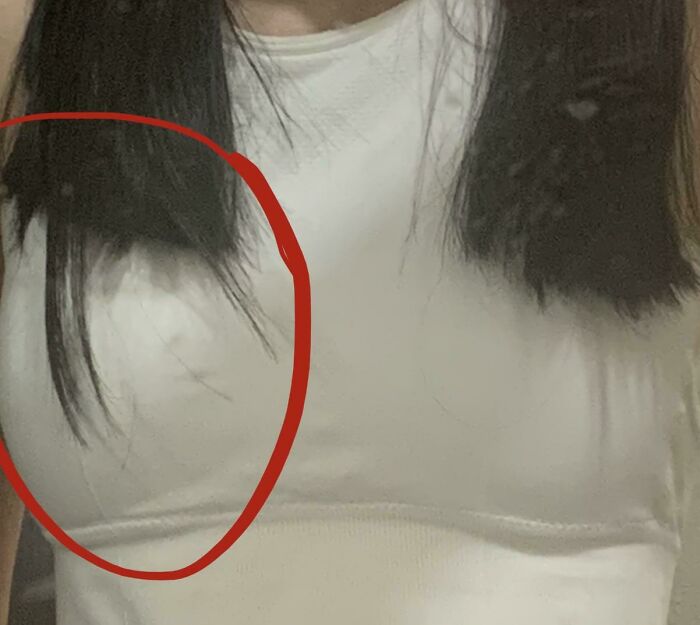 Close-up of uneven hair ends on a woman in a white shirt showing a salon glow-up gone wrong.