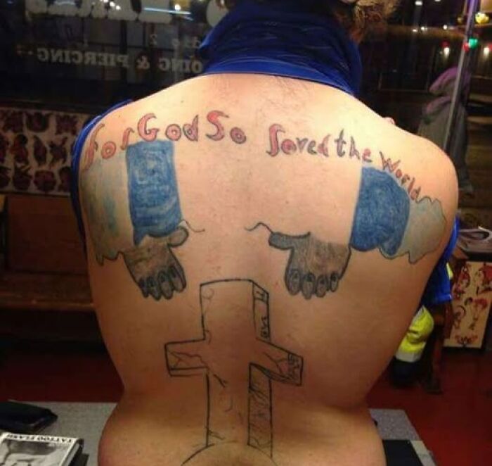 Tattoo on a person's back with poorly drawn hands, a cross, and misspelled religious text, showcasing bad tattoos.