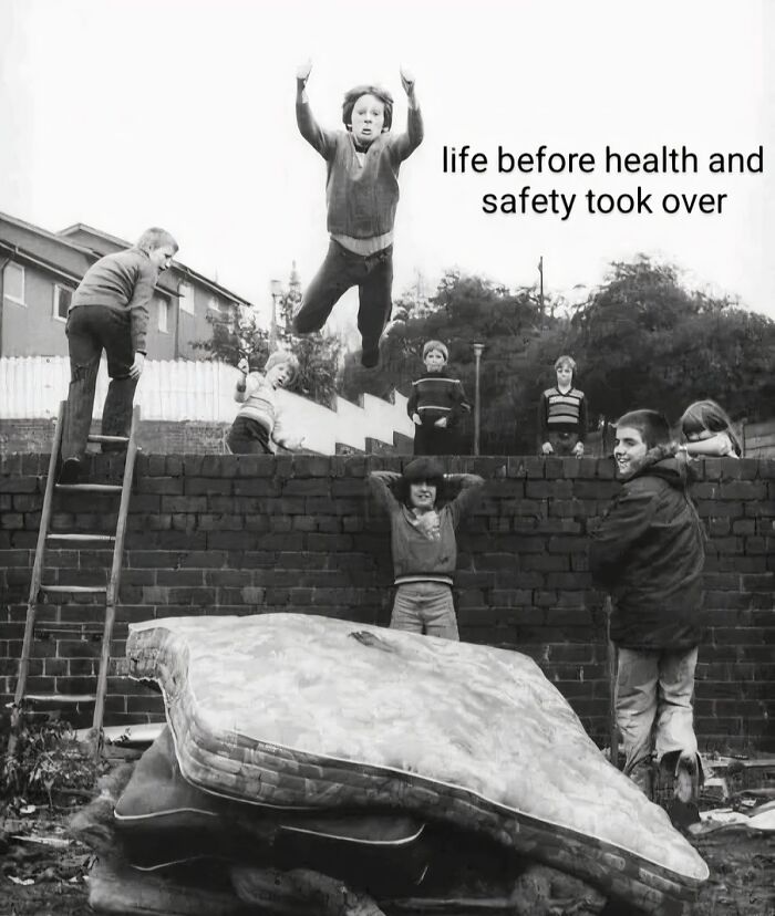 Kids jumping from a wall onto stacked mattresses outdoors, nostalgic posts capturing the magic of growing up in the ’90s.