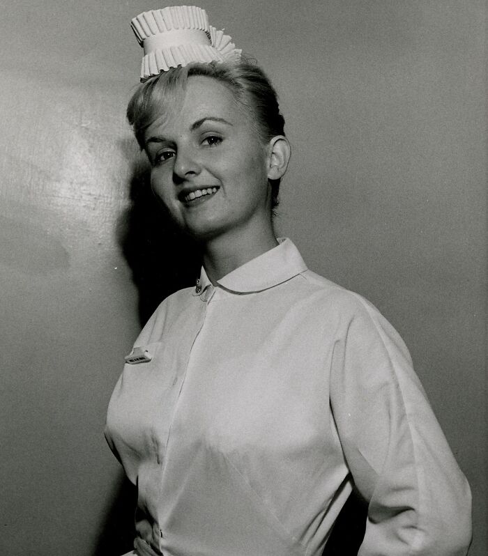 Vintage photo of a smiling nurse in traditional uniform and cap, embodying healing and hope from a past era.