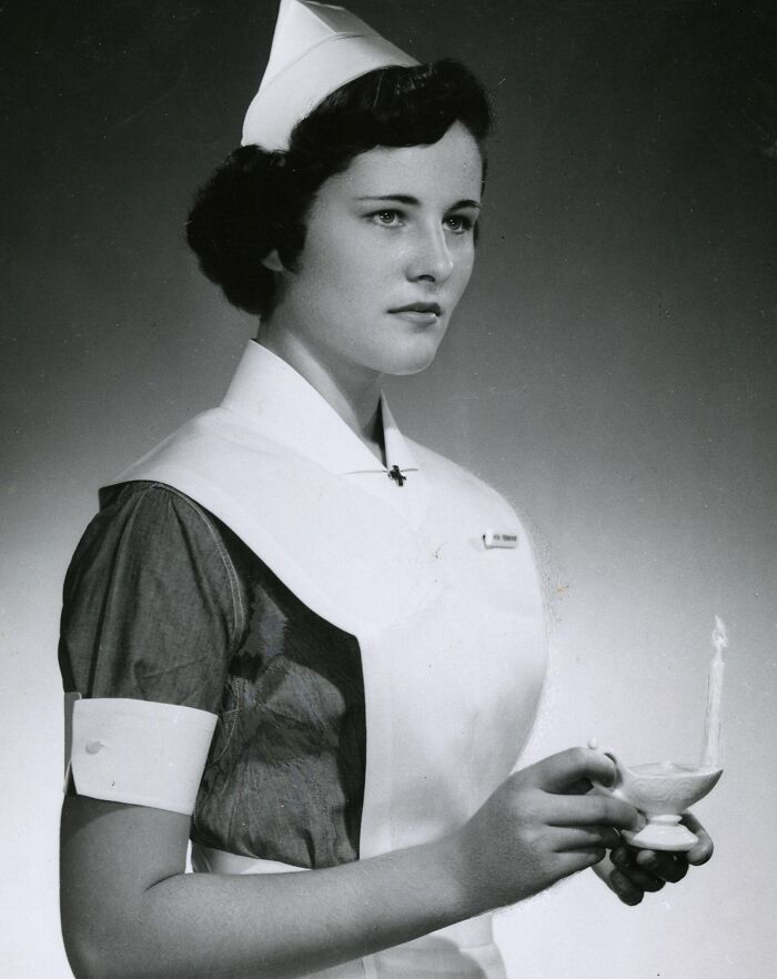 Vintage photo of a nurse holding a lit lamp, embodying healing and hope in classic nurse uniform.