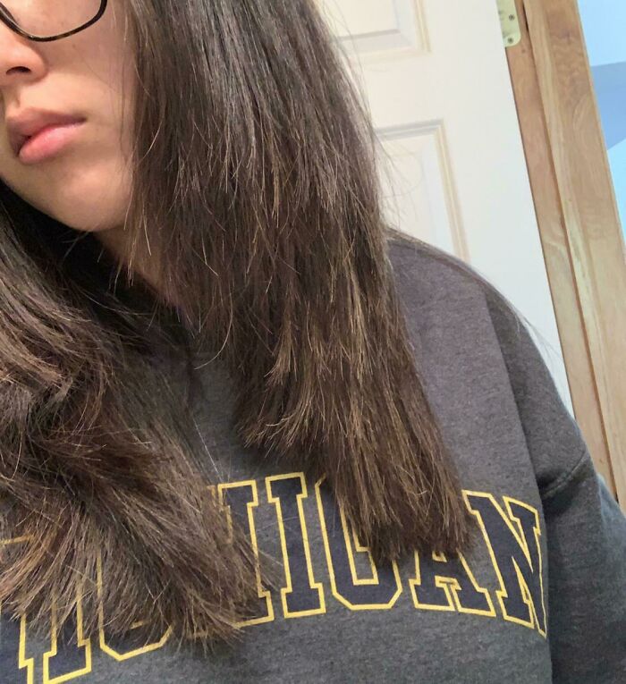 Person with uneven haircut and straight dark hair showcasing a salon glow-up gone wrong experience.