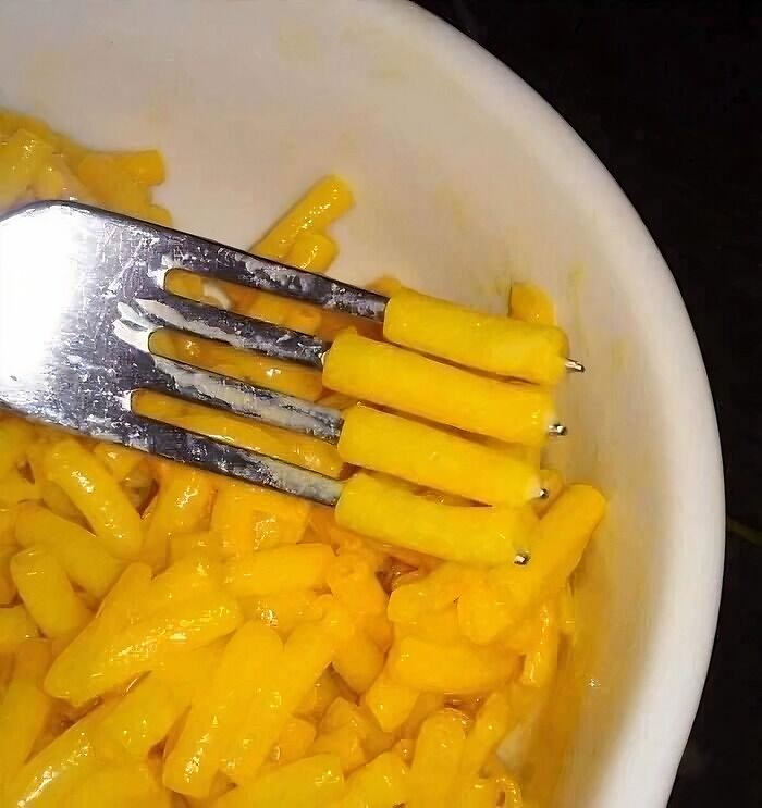 Close-up of a fork holding cheesy pasta, evoking nostalgic posts about the magic of growing up in the ’90s.
