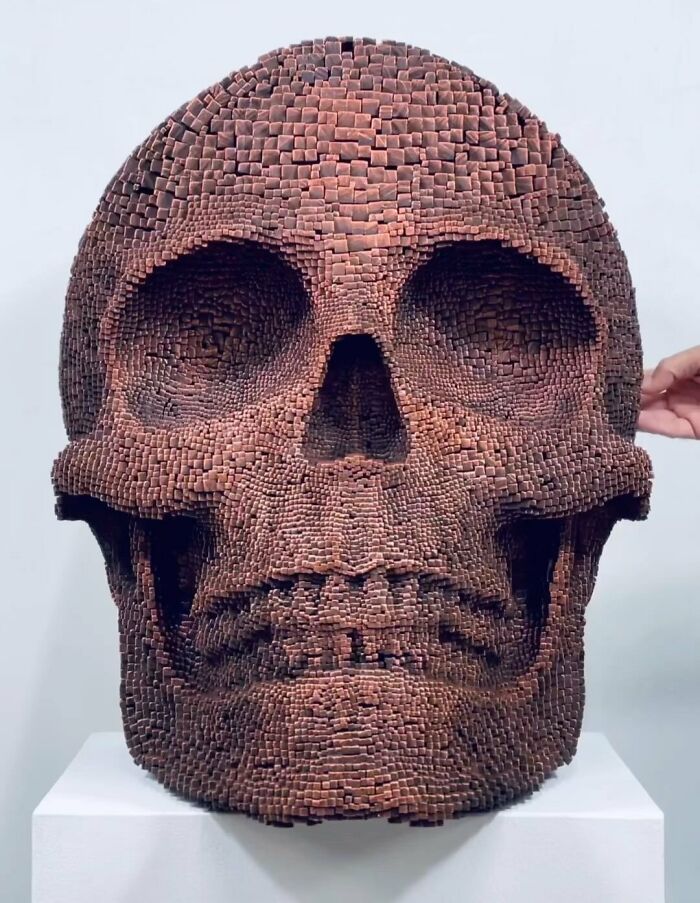 Sculpture of a 3D skull face made from wooden sticks, showcasing hypnotic and lifelike wooden art details.