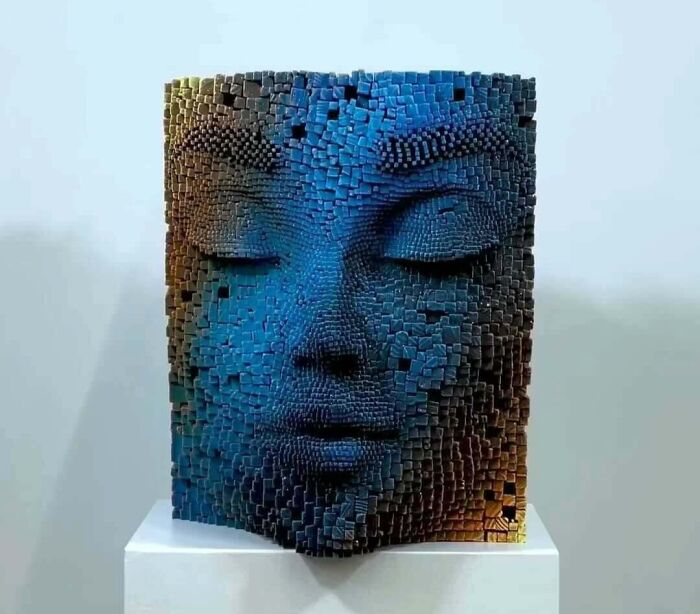 Sculptor’s hypnotic 3D face made from wooden sticks, featuring intricate texture and lifelike expression on display pedestal.