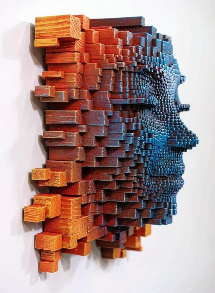 3D wooden face sculpture made from stacked wooden sticks in vibrant orange and blue colors with a hypnotic effect.