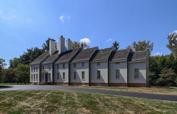 Large unhinged real estate listing with unusual architecture and multiple steep roof sections surrounded by trees.
