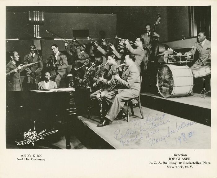 Vintage 1930s jazz orchestra performing on stage, captured in a classic black and white postcard style.