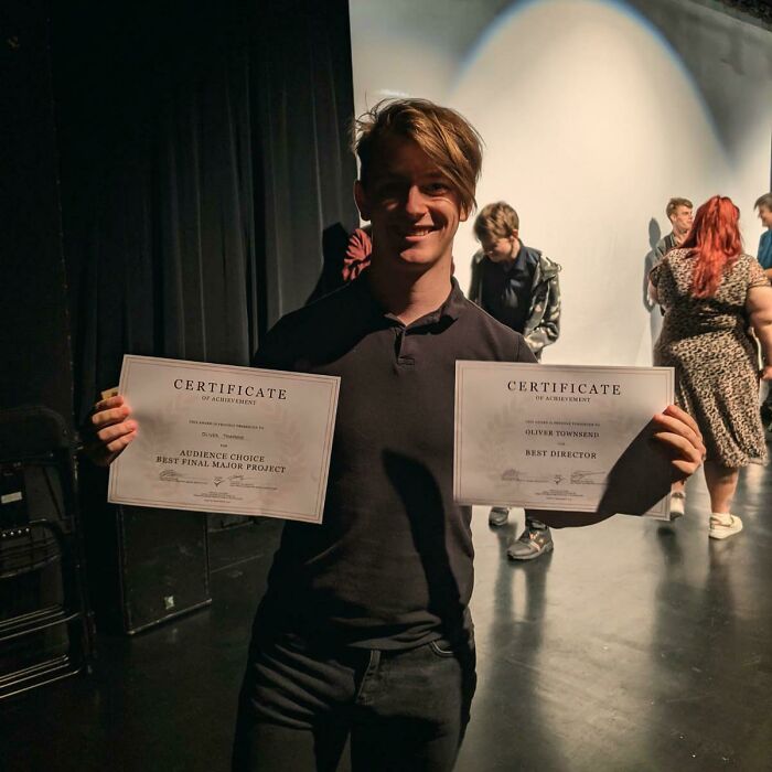 Young man smiling and holding two certificates, representing people experiencing unbelievable luck and achievement.